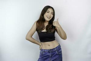 Portrait of happy young Asian woman wearing crop top showing approval gesture with her fingers, isolated over white background. Diet concept. photo