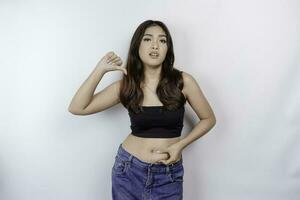 A sad young Asian woman pinching flabby skin fat belly isolated by white background photo