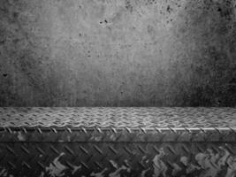 An old diamond-patterned metal slab with a cement background. photo