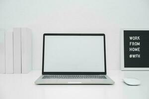 Minimalist laptop mockup white screen on white table with mouse. work from home concept photo