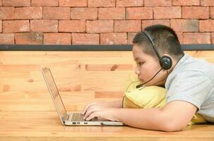 Obese boy student wear headphone study online with teacher at home, photo
