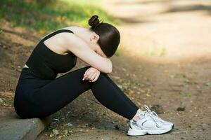 Portrait of smiling young woman in black sportswear exercising outdoors. Fitness and healthy lifestyle concept. photo