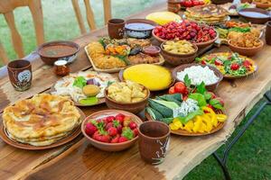 Homemade Romanian Food with grilled meat, polenta and vegetables Platter on camping. Romantic traditional moldavian food outside on the wood table. photo