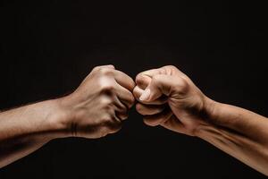 close up of a fist bump isolated on black background, hands and teamwork, support or collaboration for team building, solidarity or unity, hand connection, partnership or greeting. photo