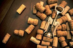 Corkscrew and wine corks on wooden table background photo