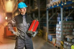 Caucasian warehouse worker with fire extinguisher. Safety concept. photo