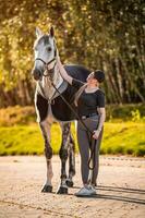 Female equestrian horse rider patting her gray horse. photo