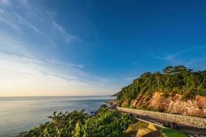 Beautiful seascape view with the mountain and sunset at noen nangphaya viewpoint chanthaburi thailand.Popular waterfront photo spot with a backdrop of the curving coastal road