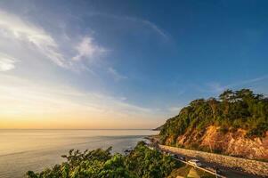 Beautiful seascape view with the mountain and sunset at noen nangphaya viewpoint chanthaburi thailand.Popular waterfront photo spot with a backdrop of the curving coastal road