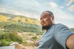 Asian fat traveler selfie himself with beautiful mountain view of Sapan Village At nan Thailand.Sapan is Small and tranquil Village in the mountain.Thailand destination travel photo