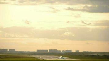 Airplane is landing to the runway at sunset. View of a commercial jet on final approach and touching down on the runway seen through airport lights Travel and wanderlust concepts video