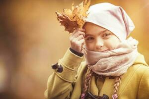 Young girl holding yellow leaf. Autumn theme. photo