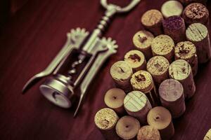 Corkscrew and wine corks on wooden table. Closeup photo. Vintage colors. photo