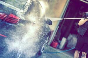 Summer car wash. Car cleaning with high pressure water. photo