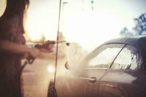 mujer Lavado su coche durante puesta de sol. yo coche lavar tema. foto