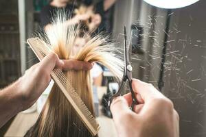 Hairdresser cut hair of a woman. Close-up. Falling hairs. photo