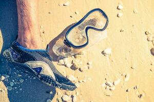 Diving Mask on Beach Sand Next to Snorkeler photo