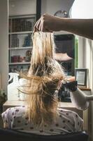 Close up of hands of hairdresser drying human hair with equipment. photo