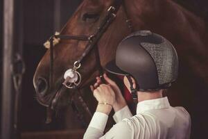 Equestrian Girl adjusting the bridle on the horse. photo