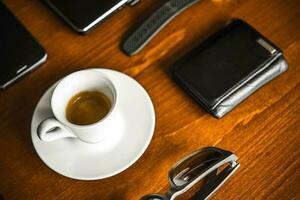 Laptop computer, coffe, watch, glasses and wallet on wooden desk photo