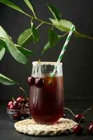 Cherry juice in a glass on a black background photo