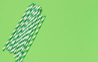 Paper cocktail straws on a green background, top view photo