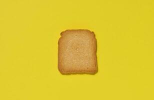 One slice of white wheat toast on a yellow background, top view photo