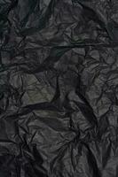Crumpled sheet of black parchment paper, abstract background photo