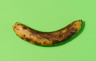 Overripe yellow banana on a green background, top view photo