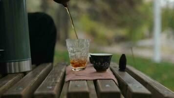 torrencial pu-erh té desde un arcilla tetera dentro un vaso taza. al aire libre té ceremonia video
