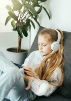 Little girl with headphones and tablet  at home photo