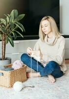 Young woman knitting warm scarf indoors photo