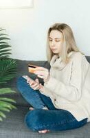 Young woman holding smartphone and banking credit card photo