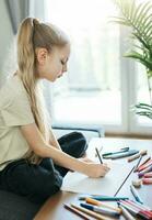 Child girl drawing with colorful pencils photo