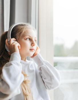Little girl with headphones indoors at home photo