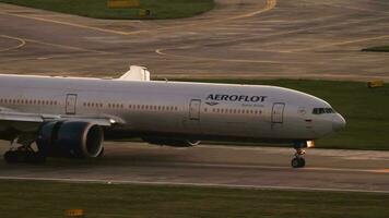 SOCHI, RUSSIA JULY 30, 2022 - Boeing 777 of Aeroflot taxiing at sunset or at dawn. Cinematic shot of passenger airliner arrival, side view. Tourism and travel concept video