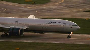 Sotschi, Russland Juli 30, 2022 - - boeing 777 von aeroflot rollen beim Sonnenuntergang oder beim Dämmerung. filmisch Schuss von Passagier Verkehrsflugzeug Ankunft, Seite Sicht. Tourismus und Reise Konzept video