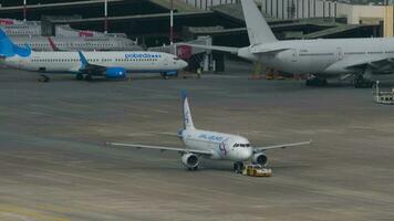 SOCHI, RUSSIA JULY 30, 2022 - Tractor pulls Airbus A320 of Ural Airlines to taxiway at Sochi airport. Tourism and travel concept video