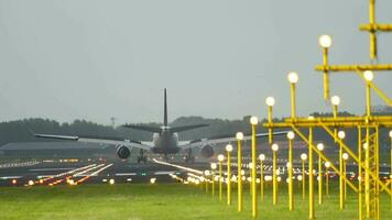 Rear view, jet plane arrival. Runway glow with landing lights. Braking with raised flaps after landing. Tourism and travel concept video