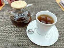 tetera con té y un taza en el mesa foto