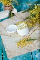 Cream with mimosa extract on a wooden surface photo