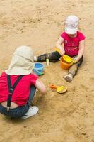 Two children are playing in the sand photo