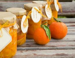 Homemade tangerine marmalade in the glass on the wooden surface photo