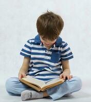 un chico es leyendo un libro en un blanco antecedentes foto