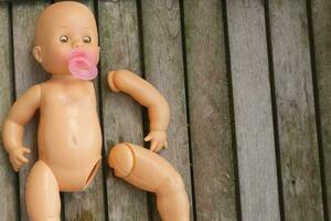 Abandoned plastic doll on wooden surface photo