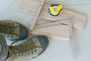 Wooden plinth, measurement band, worker's shoes. Top view photo