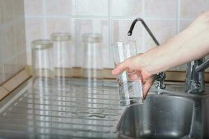 Young lady is pouring some filtered water in the glass. photo