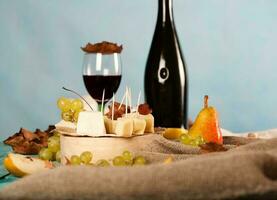 Cheese slices, pear, and grapes on a wooden stand. photo