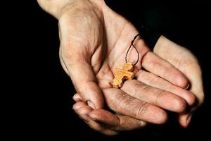 Wooden handmade cross in the palm of a peasant woman. photo