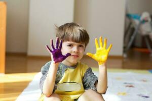 Child is painting white blanket with their palms photo